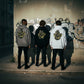 Três modelos vestem hoodies astredik cinzento, preto e branco com estampa de graffiti amarelo nas costas na rua.