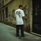 Homem de costas a usar t-shirt branca astredik com estampa 1312 em beco urbano com graffiti